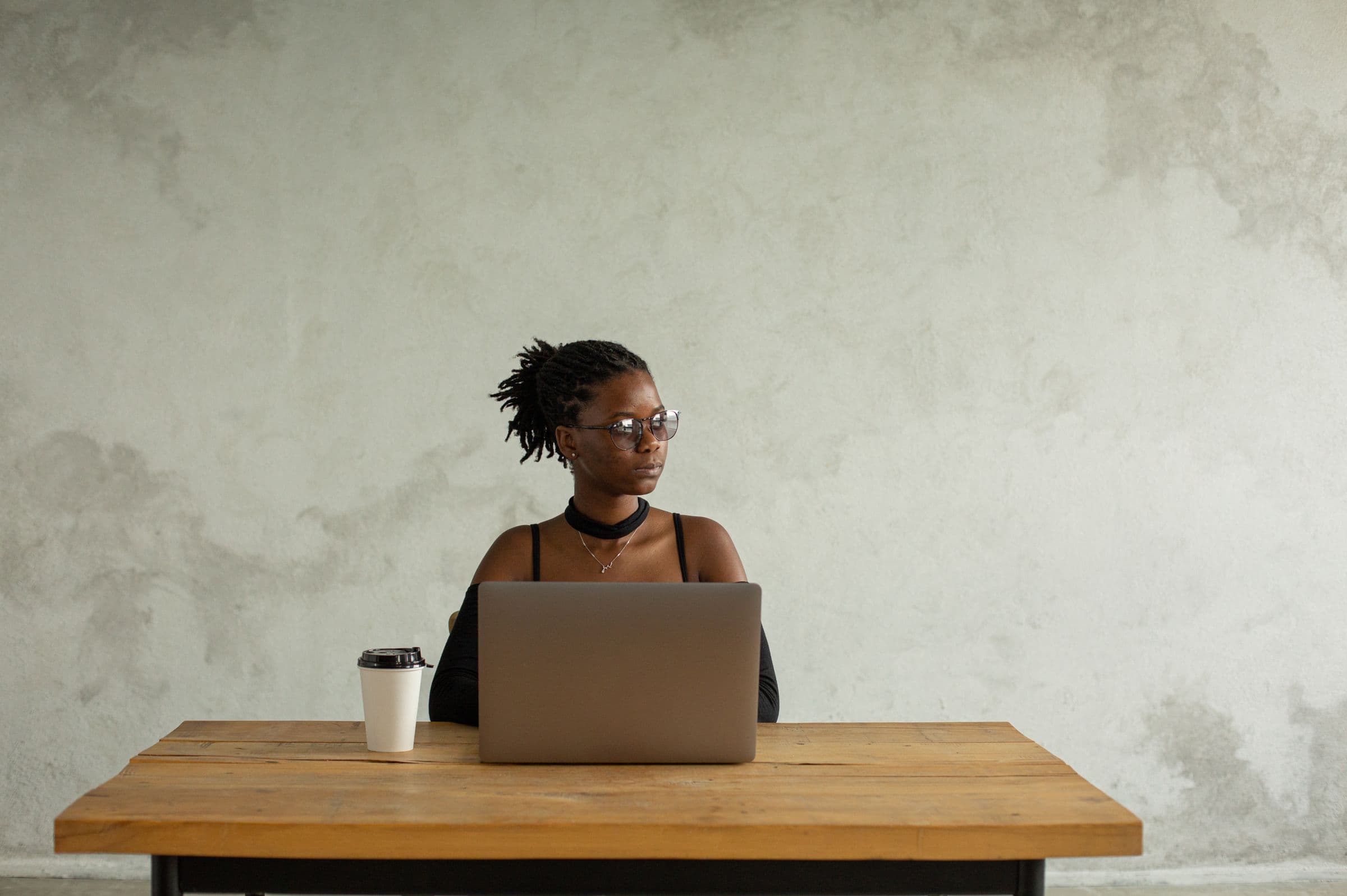 A woman studying at a laptop at a wooden desk